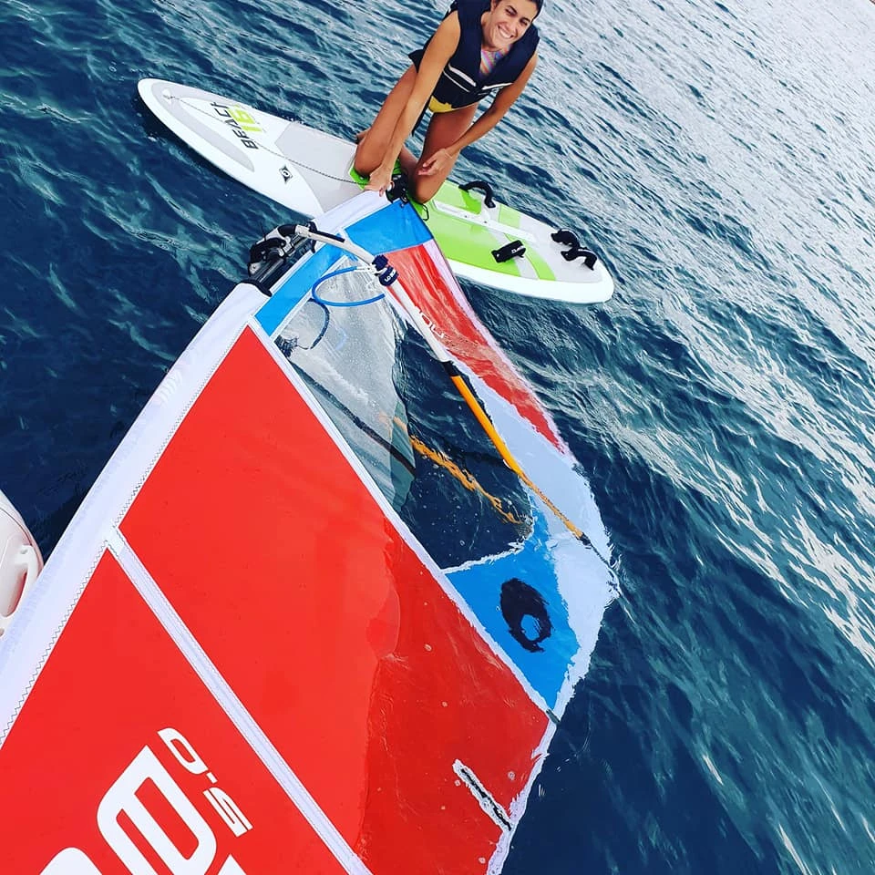 Close view of a windsurf sail and board on the water